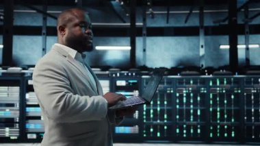 Veri merkezinde dizüstü bilgisayar kullanan, yapay zeka öğrenme modelleri kullanan bir programcı. Yapay zeka altyapı ihtiyaçlarını karşılamak için dizüstü bilgisayar kullanan işçiler, kaynak tahsisi, kamera A