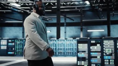 Müzik dinleyen mutlu bir yönetici, veri merkezinde sistem faaliyeti gösteren yanıp sönen ışıklarla yürüyor. Neşeli adam kulaklık takıyor. Sunucu çiftliği, kamera A 'yı denetliyor.