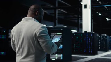 Tablet üzerinde yapay zeka sinirsel ağ teknolojisi kullanan sunucu merkezi yöneticisi. İşçi cihaz ekranında yapay zeka programlama dili kullanarak veri merkezinde yürüyor, kamera A