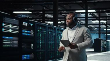 Veri Merkezi yöneticisi, kulaklık takıyor. Dar boğazları tanımlamak için tablet kullanıyor. Sunucu çiftliği bilişim uzmanı, sorun yaratan hataları dinlerken müzik dinliyor, iyileştirmeler yapılıyor, kamera A