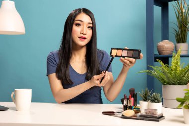 Asyalı güzellik uzmanı canlı yayın oturumunda kozmetik ürünler sunuyor, görüşlerini takipçileriyle paylaşıyor. Profesyonel makyöz güzellik kanalında en yeni göz falı paletini tartışıyor..