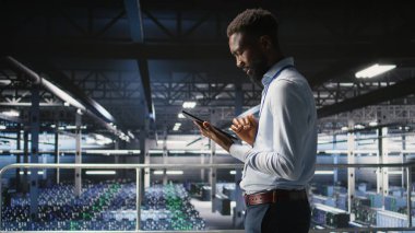 Admin on data center industrial platform analyzing infrastructure performance outputs on tablet. Server room employee doing job tasks, finetuning mainframes configurations,