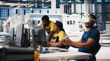 Fotovoltaik fabrikası mühendisi VR kulaklıklı PC CAD yazılımı tasarlıyor, güneş panelleri imalat fabrikasında çalışıyor. Siyah uzman sanal gerçeklikteki montaj hatlarını inceliyor. Kamera B.