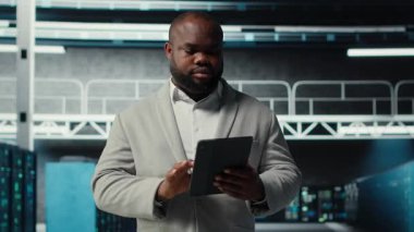 Server farm employee upgrading gear for increased processing and storage capacity. Data center IT professional ensuring error free and scalable networks for intense computational demands, camera B
