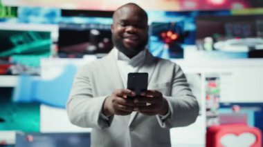 Telefonla yazarken gülümseyen, internet içeriğiyle boş zamanların tadını çıkaran biri. Neşeli bir adam akıllı telefonun önünde videolarla dolu olan sosyal medya uygulamasına göz atıyor.