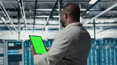 Veri merkezinde afet kurtarma planlarını geliştirmek için yeşil ekran tableti kullanan bir mühendis. BT sunucu çiftliği testinde başarısız olma senaryoları, modelleme aygıtı, bozulmalar sırasında verilerin korunması, kamera B