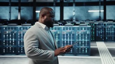 Yüksek teknoloji sunucu merkezinde çalışan teknisyen kusursuz veri akışını sağlamak için tablet üzerindeki verileri analiz ediyor. Veri merkezindeki ekipmanları inceleyen bilişim uzmanı, sistem bütünlüğü ve güvenliğinin sağlanması, kamera A