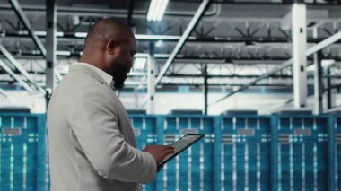 Keyifli sunucu odası mühendisi tablet üzerinde yazılım kullanarak arka uç işlemleri yapıyor. Jolly veri merkezi programcısı, aygıt, kamera B kullanarak hataları düzeltmek için yazılım yamaları derliyor