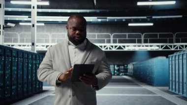 Gülümseyen veri merkezi teknisyeni tablet kullanarak yükseltilmiş sunucu rafları kuruyor. Otomasyon araçlarını kullanarak altyapı performansını izleyen neşeli sunucu odası çalışanı, kamera A