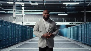 Cheerful admin walking in data center workplace, checking gear for system stability. Jolly IT professional overseeing server hub, configuring racks, optimizing performance, camera A