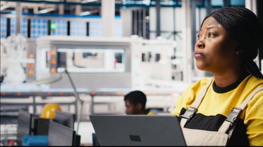 Photovoltaics fabrikası yöneticisi test denetimi için dizüstü bilgisayar kullanarak üretim sürecini inceliyor. Güneş panelinin çevre dostu yenilenebilir enerji konfigürasyonlarını geliştiren bir kadın. Kamera B.