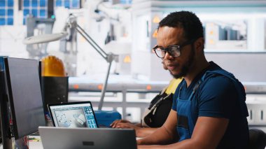 Siyah mühendis güneş sistemi parametrelerini yenilenebilir enerji tesisinde PC kullanarak endüstriyel iş istasyonuna giriyor. Teknisyen yazılım yönetimi yoluyla sürdürülebilir üretimi destekliyor. Kamera A.