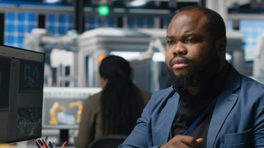 Siyahi endüstriyel uzman, güneş paneli fabrikası kurarak, temiz sürdürülebilir enerji üzerinde çalışarak, bilgisayar üzerindeki montaj sürecini inceliyor. Üretim akışı için mühendislik yeniliği. Kamera B.