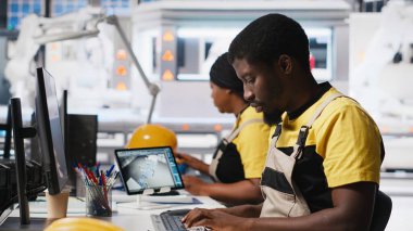 Afrikalı Amerikalı teknisyen, gelişmiş izleme ve üretim araçları kullanarak PC istasyonundaki yenilenebilir enerji ölçümlerini değerlendiriyor. Mühendis güneş enerjisinin hassasiyetini geliştiriyor. Kamera A.