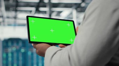 Veri merkezi bilişim uzmanı, performans gösterge panellerini gözden geçirmek için model tablet kullanıyor. Sunucu odası yöneticisi sistemleri denetliyor, krom anahtar aygıtının altyapısını inceliyor, kamera B kapatma