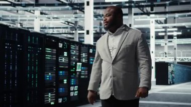 Gülümseyen mühendis, veri merkezindeki iş yerinde birden fazla dizi tam teşekküllü süper bilgisayarla yürüyor. Dijital depolama sistemleri için inşa edilmiş neşeli çalışan denetleme sunucu odası, kamera A