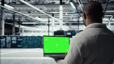 Veri merkezi yönetimi nöral ağ yapay zekasını izlemek için izole ekran bilgisayarı kullanıyor. Sunucu odası çalışanı, platformlara güç veren makine öğrenme süreçlerini denetlemek için maket defteri kullanıyor. Kamera A