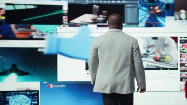 Adam, video ve sosyal medya videoları ile çevrili dijital video baykuşağının önünde duruyor. Kullanıcı, multimedya gösterge paneli, kamera A üzerinden anında binlerce eğlence seçeneğine erişiyor