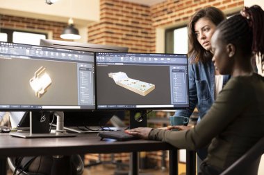 Masada çalışan siyah ve beyaz kadın mühendisler bir inşaat şirketi için 3 boyutlu tasarım geometrisi geliştirmeye çalışıyorlar. Afrikalı Amerikalı geliştirici çoklu monitörde kaba yazılım kullanıyor..