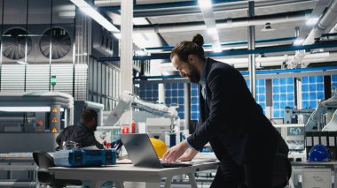 Sanayi işyerindeki güneş enerjisi sistemlerini denetleyen idari danışman, sürdürülebilir enerji gelişimi için stratejik planlamayı vurguluyor. Temiz enerji üretim hattında yenilik. Kamera A.