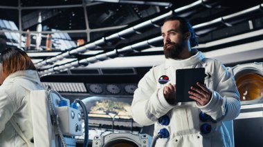 Astronot uzay istasyonu dışında planlanan operasyonlara başlamadan önce görev planını tabletten okuyor. Kozmonot cihazdaki analizleri kontrol ediyor, gezegene indikten sonra ayrılmaya hazırlanıyor.