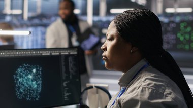 Veri merkezi sistem yöneticisi PC kullanarak nöral ağ yapay zeka görüntülemesini izliyor. Sunucu odasında Afrika kökenli Amerikalı bir kadın bilgisayarla donanımlı makine öğrenme işlemlerini denetliyor. Kamera A