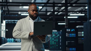 Bilgisayar kullanarak veri merkezinde programcı, ekipman arızası senaryolarını test ediyor. Sunucu çiftliği bilişim uzmanı defter üzerinde yazılım kullanıyor, veri erişiminin sağlanması, kamera B