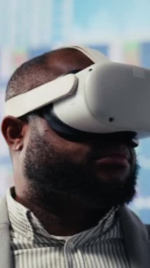 Vertical Video Afrikalı Amerikalı girişimci VR kulaklığı kullanarak bilgi grafiklerini gözden geçirir, iş geliştirme ve üretkenlik için aylık büyük veri raporlarını inceler. Yüksek teknoloji yöneticisi. Kamera B.