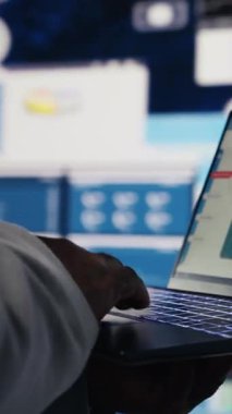 Dikey Video Siyah işletme yöneticisi yeni bir vizyon oluşturmak için büyük veriler ve KPI ölçümleri okuyarak fintech sezgisini incelemek için dizüstü bilgisayarını kullanıyor. Liderlik ve yönetim becerileri. Kapatın. Kamera B