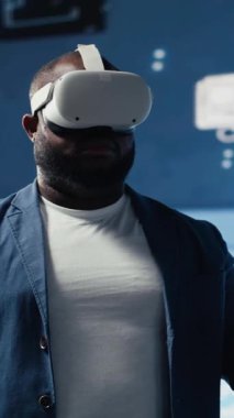 Dikey Video Siyah iş adamı, dijital veri işleme ortamında veri bilimi, otomasyon ve yapay zeka etiğini keşfetmek için ileri teknoloji VR kulaklık araçları kullanıyor. Makine öğrenimi üzerine çalışır