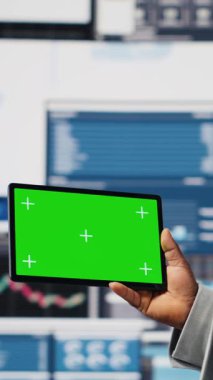 Dikey Video Siyah iş adamının elinde yeşil ekranlı ve kontrol panelli bir cihaz var. Ekonomi sektöründe başarı elde etmek için iş verimliliği sağlıyor. Performans ölçümleri ve içgörü. Kamera.