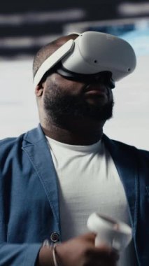 Dikey Video Afrikalı Amerikalı yazılım geliştiricisi sanal gerçeklik kulaklığını kodlama, yüksek teknoloji arayüzü çalışma alanı için kullanır. Terminal pencerelerle çevrili, dijital programlama kültürünü temsil ediyor