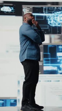 Dikey Video Afrikalı Amerikalı mühendis otomasyon için programlama dilini analiz ediyor. Arkasında gelecekteki arayüzü olan veri bilimi. Erkek teknoloji uzmanı yapay zeka ve kod parçacıklarıyla başarılı oluyor.