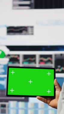 Dikey Video Siyah iş adamının elinde yeşil ekranlı ve kontrol panelli bir cihaz var. Ekonomi sektöründe başarı elde etmek için iş verimliliği sağlıyor. Performans ölçümleri ve içgörü. Kamera.