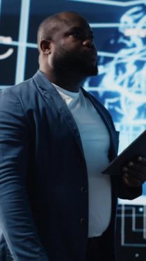 Dikey Video Genç siyah teknisyeni yapay zeka veri görselleştirme ve sinirsel ağlar platformlarını inceliyor, akıllı teknoloji siber uzay sistemleri. Makine öğrenimi, bulut hesaplama ve algoritmaları inceler