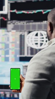 Dikey Video Afrikalı Amerikalı iş adamı cihazın izole edilmiş bir kopyasını kullanıyor, torpido gözündeki büyük veri bilgilerini inceliyor. Stratejik karar verme, üretkenlik ve büyüme gösteren genç yetişkinler. Kamera.