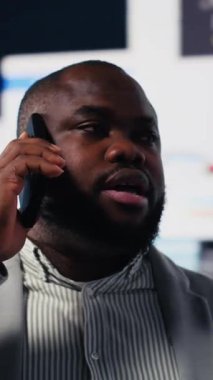 Dikey Video Afrikalı Amerikalı girişimci iş geliştirme için yeni bir vizyonla telefonda konuşuyor, performans ölçümleri için çok çalışıyor. Büyüme için tahmin ve proje planlaması