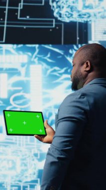 Dikey Video Afrikalı Amerikalı mühendis, veri işleme otomasyonu ve yenilikleri için öngörücü analitikleri ve nöral ağları inceleyen, izole edilmiş model ekran tableti gösteriyor. Sibernetik