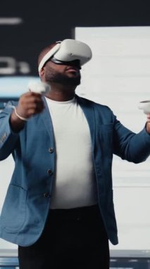 Dikey Video Afrikalı Amerikalı yazılım geliştiricisi sanal gerçeklik kulaklığını kodlama, yüksek teknoloji arayüzü çalışma alanı için kullanır. Terminal pencerelerle çevrili, dijital programlama kültürünü temsil ediyor