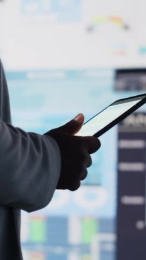 Dikey Video Siyah erkek girişimci finans grafikleri ve KPI modellerini inceleyerek, fintech materyalleri ve tahmin araçları için stratejik içgörü ile iş performans raporlarını gözden geçiriyor. Yönetim