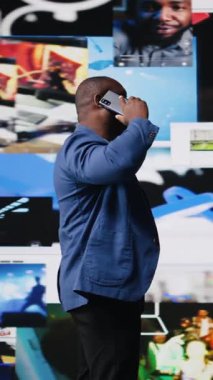 Dikey Video Afrikalı Amerikalı adam, mobil yüksek teknoloji platformları vasıtasıyla telefon bağlantısını ve online iletişimi kullanıyor. Sosyal ağlar uygulamaları aracılığıyla çevrimiçi etkileşim