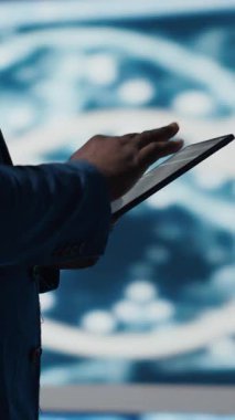 Fütüristik dijital çalışma alanında dikey video, siyah geliştirici programlama yazılımı ve kod parçalarını araştırıyor. Teknoloji profesyoneli yenilik, siber güvenlik, otomasyon ve geliştirmeyi somutlaştırdı