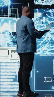 Dikey Video Afrikalı Amerikan teknoloji uzmanı yapay zeka etiği ve sinirsel ağlar üzerinde çalışıyor, makine öğrenme sistemleri için sanal zeka beyin araçları. Gösterge panelinde algoritmik düşünme gelişimi