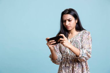 Akıllı telefondaki video oyunlarıyla eğlenen mutlu Hintli kadın, boş zamanların tadını çıkarıyor. Oyuncu telefonda oyundan zevk alıyor, düşmanları yenmek, stüdyo geçmişine karşı durmak..