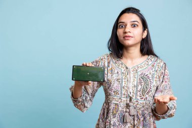 Krom anahtar sunan pozitif mutlu kız cihazda izole ekran, stüdyo arka planına karşı bir reklam yapıyor. Reklam markaları için kullanılan neşeli Hintli kişi.