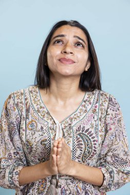 Stüdyoda elleri kavuşturulmuş, Tanrı 'ya dua eden, umutsuzca bakan ve onunla konuşan biri. İnancını, bağlılığını ve saygısını gösteren dindar genç bir kız..