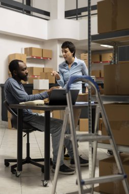 Masadaki çeşitli ekip ürün ve kutularla dolu sıkıca paketlenmiş bir depoda dağıtımı garanti altına almak için sipariş işlemlerini tartışıyor. Küçük ölçekli bir işletmenin organize yapısı.