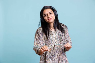 Elektronik müzik çalan ve havada el sallayan mutlu bir kadın stüdyoda harika dans hareketleri yapıyor. Neşeli, kendine güvenen, kulaklık takan ve şarkılarını kamerada dinleyen bir kız..