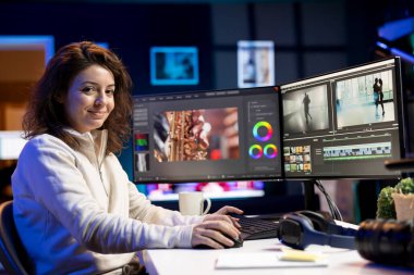 Prodüksiyon ekipleri tarafından çekilen görüntüleri güncellemek için özel efektler kullanan ve yazılım paketlerini düzenleyen neşeli video editörünün portresi. Multimedya ajansındaki mutlu videograf bitirme projesi