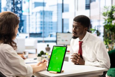 Kariyerinde ilerlemek isteyen iş görüşmesi adayı, yeşil ekran tableti kullanan İK çalışanıyla konuşmak. Elemanla konuşan adam işe alınmak için CV 'sini kroma anahtarıyla kontrol ediyor.